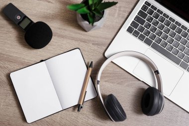 gazetecilik ve blog konsepti - dizüstü bilgisayarı, mikrofonu, kulaklığı, not defteri ve kalemi ahşap masa arkasında olan işyeri manzarası