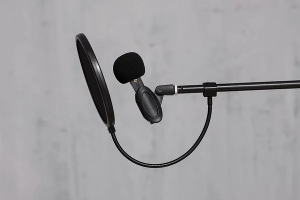 creativity, content making, podcast and blogging concept - microphone and pop filter on the stand over grey wall background