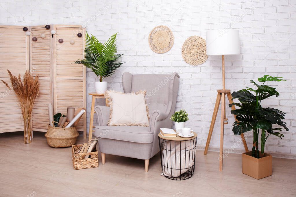 Stylish room with armchair, lamp and plants over brick wall background