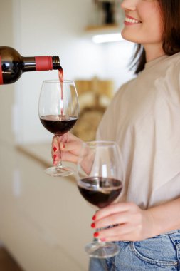 Kırmızı şarabı kadın ellerinde bardaklara doldurun.