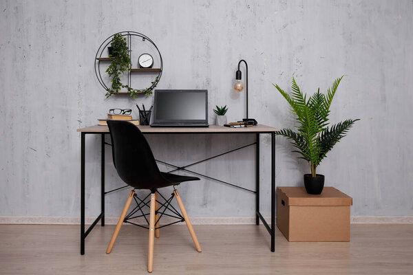 Workplace with table and laptop in office over concrete wall