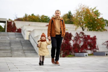 Aile, ilgi ve mutluluk konsepti - mutlu baba ve küçük kızı sonbahar parkında yürüyorlar
