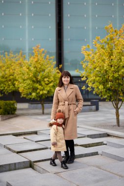 Güz parkında yürüyen güzel bir anne ve küçük tatlı bir kızın tam boy portresi.