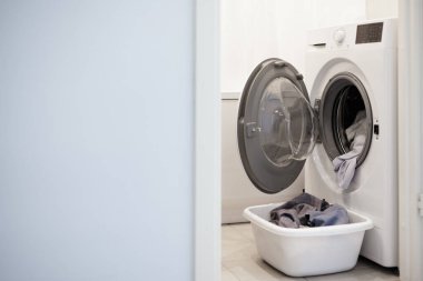 Çamaşır makinesi ve çamaşır sepeti banyoda, mavi duvar arkaplanındaki boşluğu kopyala