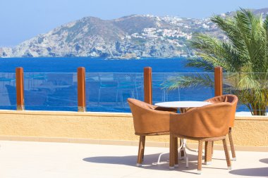 Tablo ve Deniz Manzaralı terasta üç sandalyeler