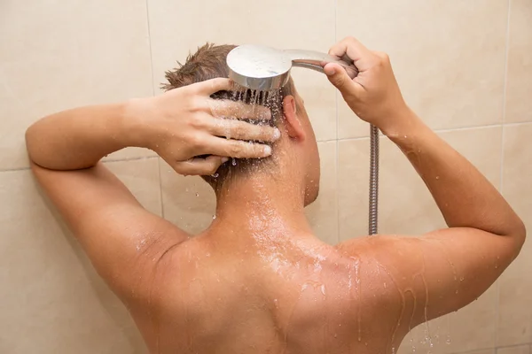 Back view of young man washing head in bathroom - Stock-foto