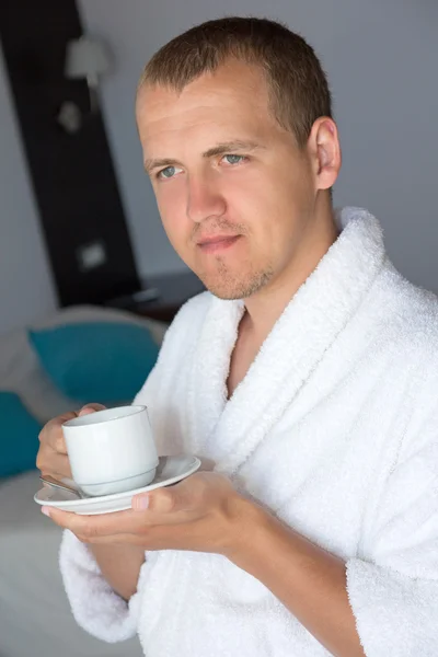Man in bathrobe drinking coffee in hotel room — Stock Photo, Image
