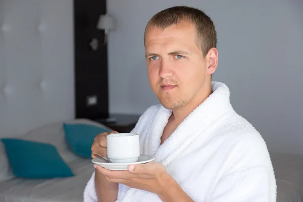 Happy man in bathrobe drinking coffee in hotel room — Stock Photo, Image