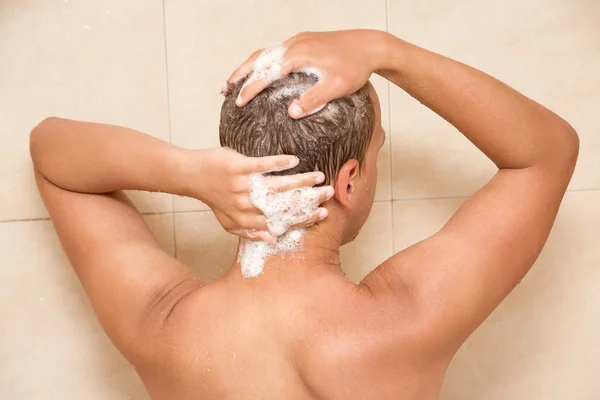 Vue arrière du jeune homme, laver les cheveux dans la douche — Photo