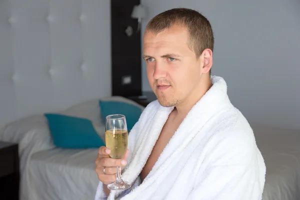 Lycklig man i morgonrock dricka champagne i hotellrum — Stockfoto