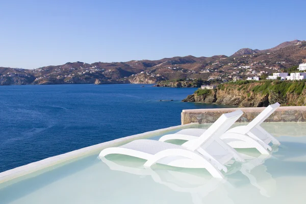 Zwei weiße Stühle im Pool mit Blick auf das Meer in Griechenland — Stockfoto