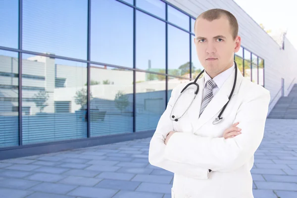 Mężczyzna lekarz stoi na ulicy przed budynek nowoczesny szpital — Zdjęcie stockowe
