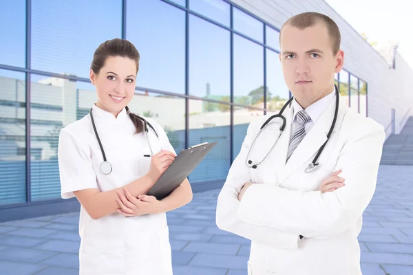 Two doctors standing against modern hospital building — Stock Photo, Image