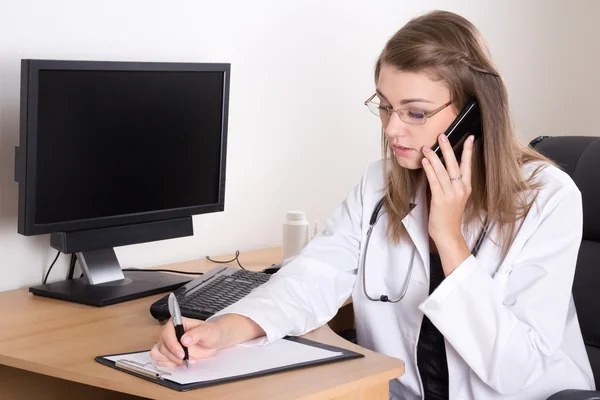 Beautiful woman doctor talking on phone in office — Stock Photo, Image