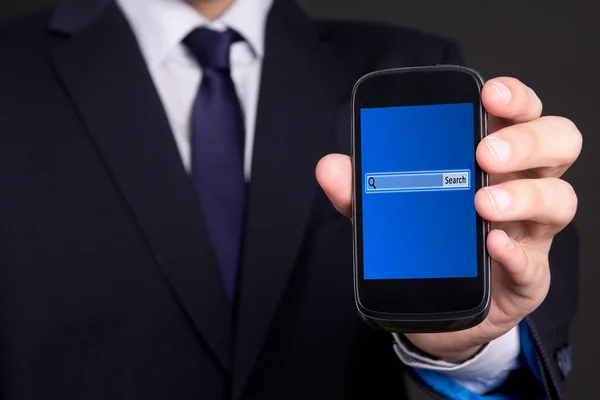 Teléfono móvil con la barra de búsqueda en la pantalla de la mano del hombre de negocios —  Fotos de Stock