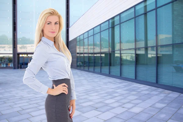 Business blond woman standing on street against modern building — Stock Photo, Image