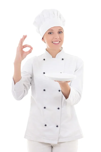 Young woman chef in uniform holding empty plate and showing ok s — Stock Photo, Image
