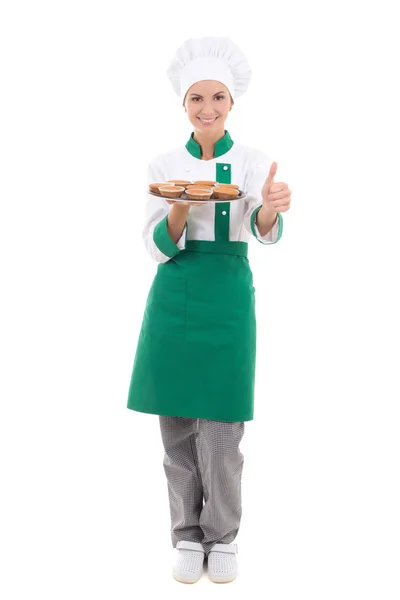 Счастливая женщина повара в однородном подносе холдинга с кексами и большими пальцами — стоковое фото