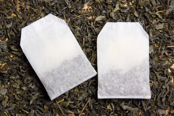 tea bags over dried tea leaves background
