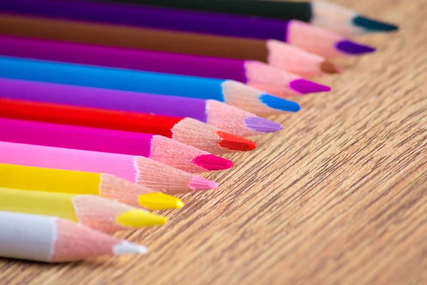 Rangée de nombreux crayons de dessin colorés sur table en bois — Photo