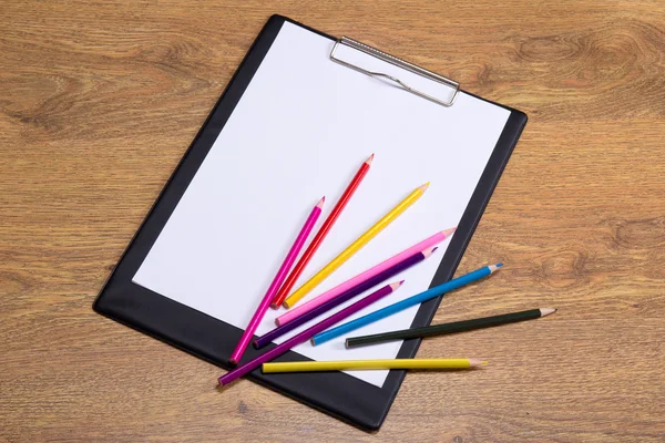 Colorful drawing pencils and clipboard with blank paper on woode — Stock Photo, Image