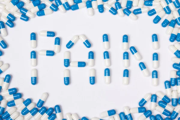 Pijn word tekst gemaakt van blauwe tabletten, pillen en capsules — Stockfoto