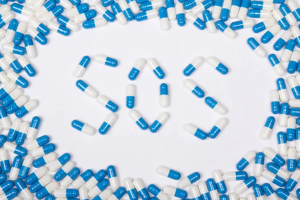 Sos word text made of blue tablets, pills and capsules – stockfoto