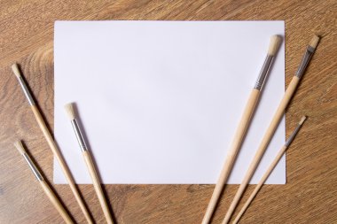 Boya fırçaları ve ahşap arka plan boş beyaz kağıda