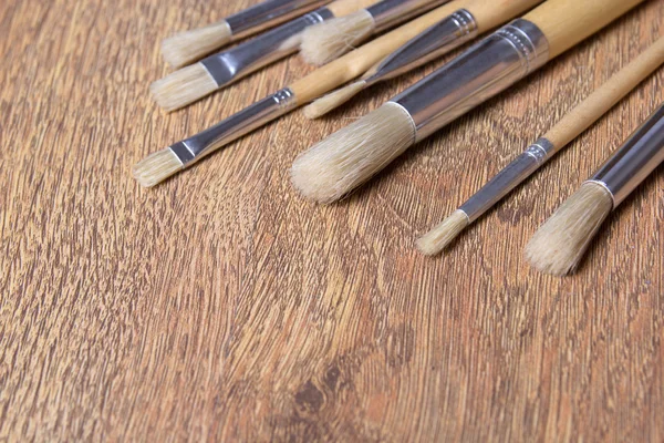 Close up of paint brushes on wooden table — Stock Photo, Image