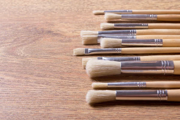 Row of paint brushes on table background — Stock Photo, Image