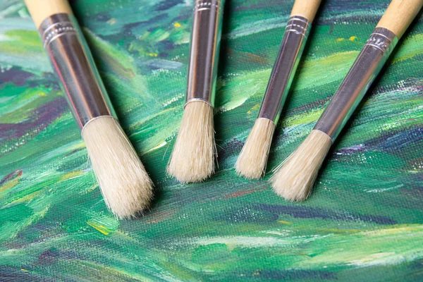 Close up of paint brushes on green canvas background — Stock Photo, Image