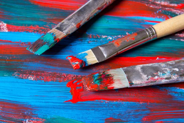 Brushes on acrylic paint background with blue and red strokes — Stock Photo, Image