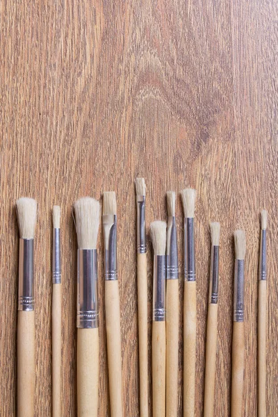 Row of wooden paint brushes on table background — Stok Foto