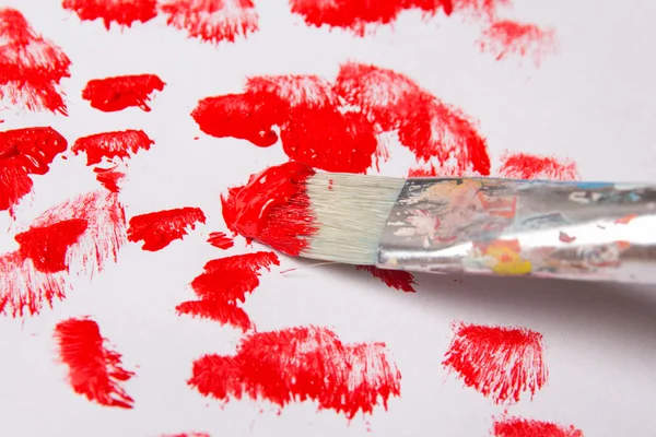 Close up of paint brush with red paint strokes over white — Stock Photo, Image