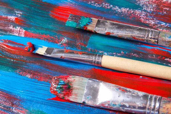 Brosses et fond de peinture acrylique avec des traits bleus et rouges — Photo