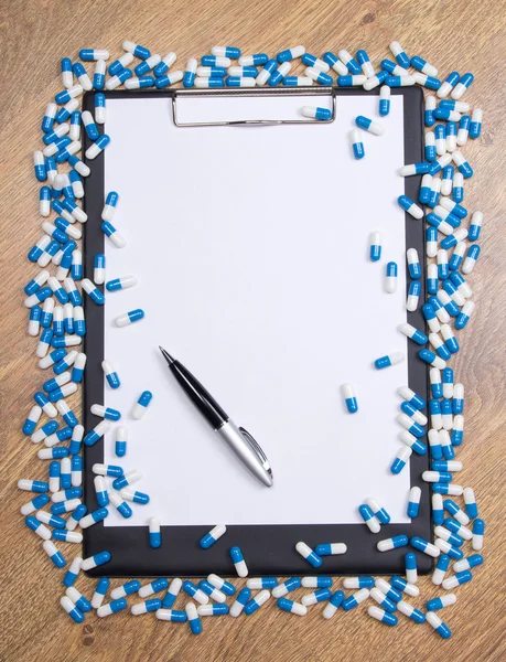 Heal of tablets, clipboard and pen on wooden table — Stock Photo, Image