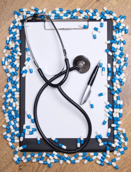 Heal of tablets, clipboard, stethoscope and pen on wooden table — Stock Photo, Image