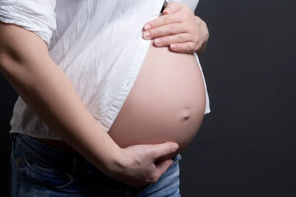 Nahaufnahme der Bauch der schwangeren Frau über grau — Stockfoto
