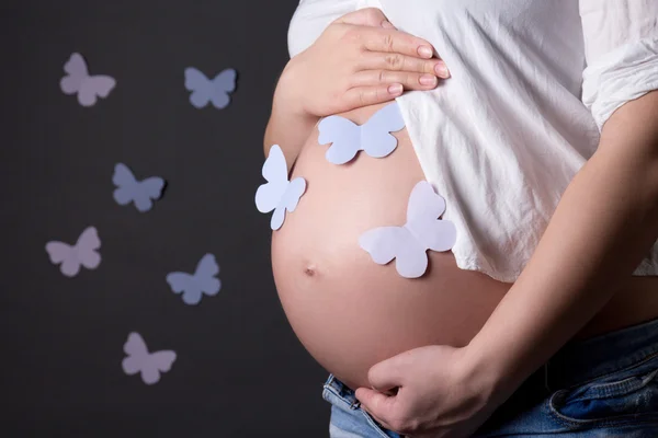 Hamile kadının karnında üzerinde gri renkli kelebekler ile — Stok fotoğraf