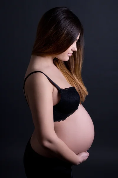 Ung vacker gravid kvinna i underkläder över grå — Stockfoto