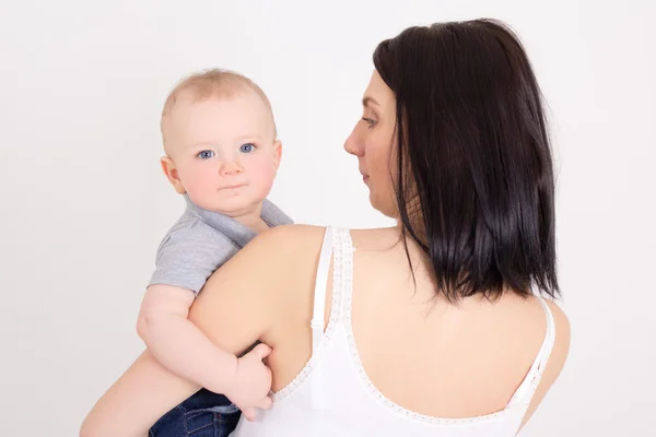 Retrato de uma jovem mãe segurando seu filho pequeno sobre branco — Fotografia de Stock