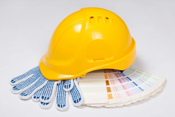 Builder's yellow helmet, work gloves and colorful palette over w — Stock Photo, Image