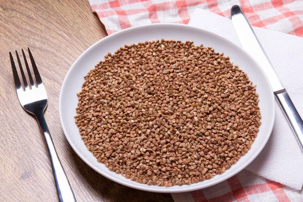 Close up of buckwheat in plate with fork and knife — Stock Photo, Image