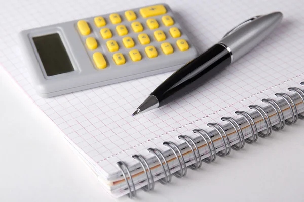 Caderno com páginas verificadas, caneta e calculadora — Fotografia de Stock