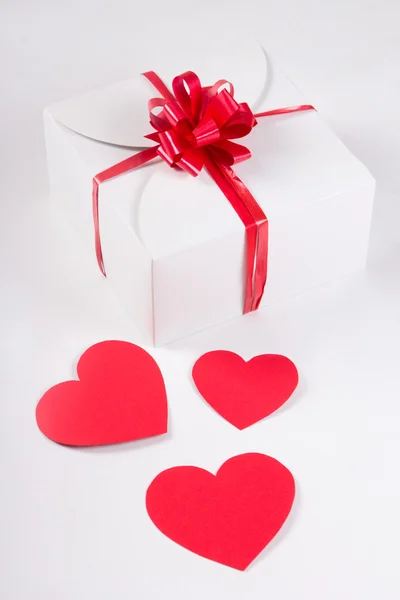 Подарочная коробка с красными бумажными сердцами по белому — стоковое фото