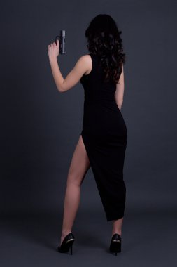 Seksi kadın gizli ajan grey üzerinde silahla poz arkadan görünüm