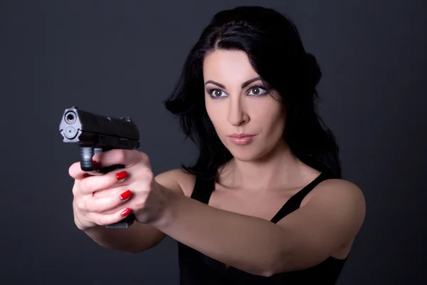 Young sexy woman aiming with gun over grey — Stock Photo, Image