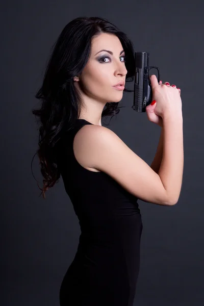 Retrato de agente secreto mulher sexy, posando com arma sobre cinza — Fotografia de Stock