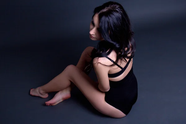 Giovane bella donna sexy in lingerie nera, seduta sopra grey — Foto Stock