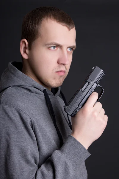 Criminoso de jovem com arma sobre cinza — Fotografia de Stock